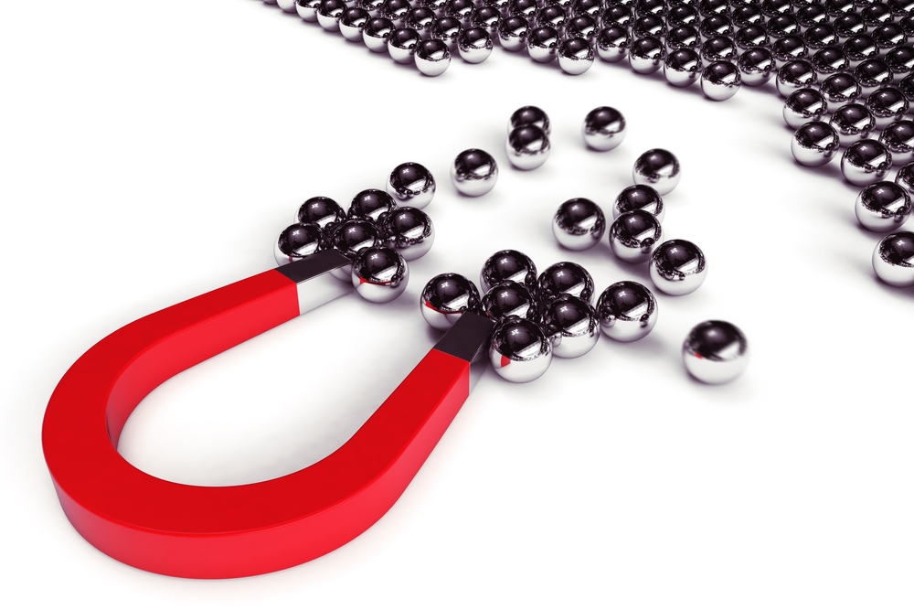 black substance creating a "pincushion" pattern above a cube magnet